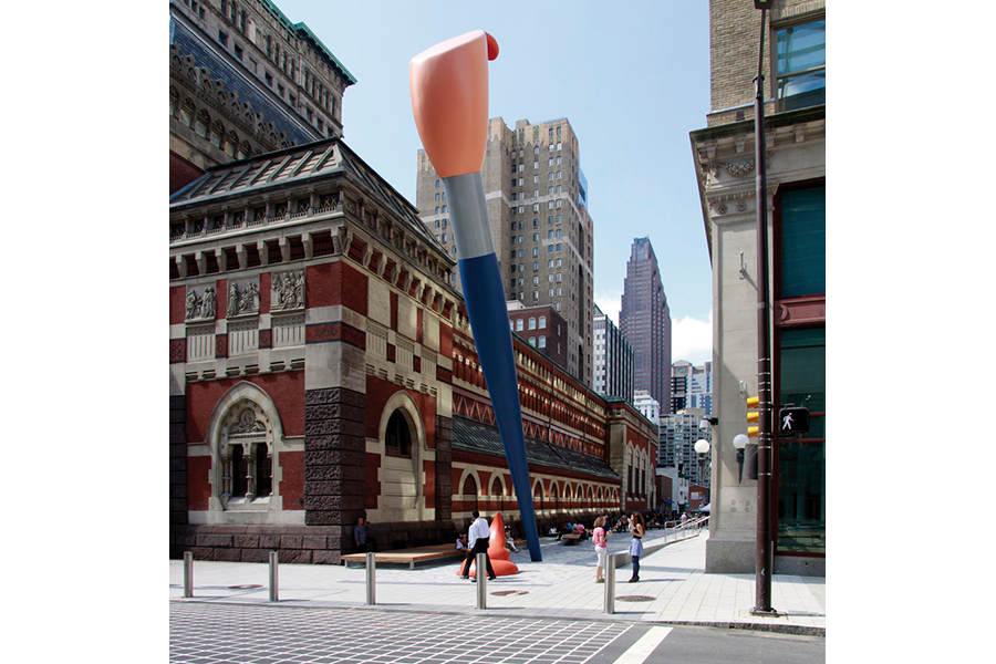 A street-level view of a giant paintbrush sculpture in a modern plaza next to an ornate red brick building.