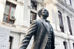 low-angle, close-up shot of the bronze statue of Octavius Catto, looking upward against the backdrop of Philadelphia’s City Hall.