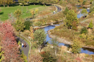 An elevated view of a winding river in a park during autumn, featuring walking paths and colorful fall foliage.